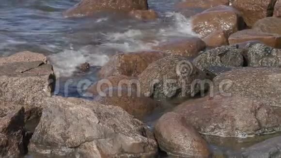 在夏季刮风的日子里海浪冲刷波罗的海沿岸的石头视频的预览图