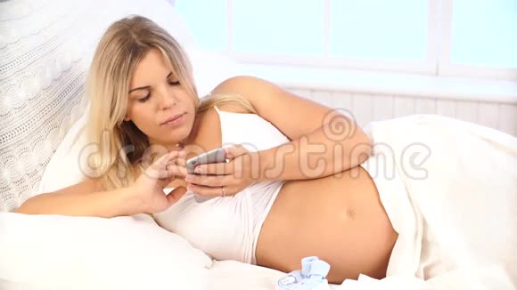 孕妇在家里用智能手机躺在床上视频的预览图
