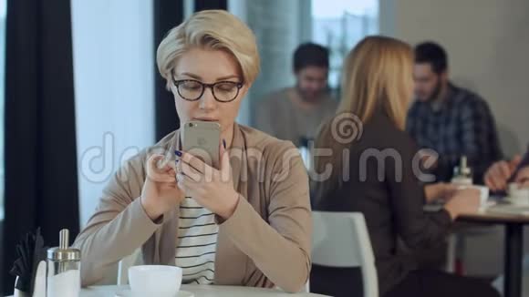 在咖啡馆喝咖啡和使用手机的年轻女子视频的预览图