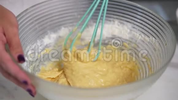 女人在厨房里用搅拌器准备面团混合配料自制食物慢镜头视频的预览图