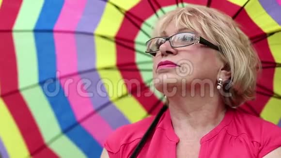 戴着五颜六色雨伞的眼镜的老妇人视频的预览图