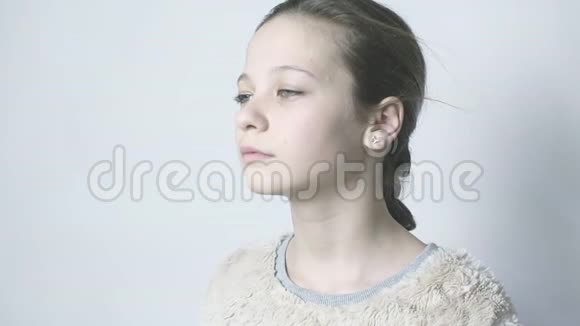 年轻的女孩轻松地站在白色的背景下一个大眼睛的漂亮女孩站在风中视频的预览图