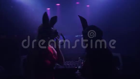 戴着野兔面具的麦姑娘和贾姑娘在夜总会的转盘上表演耳机视频的预览图