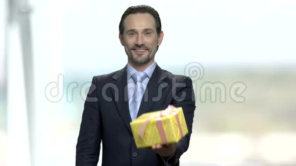 英俊的微笑商人带着礼品盒视频的预览图