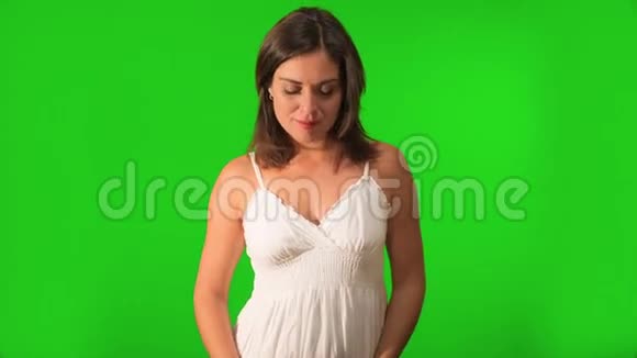 美丽的孕妇抱着她的肚子在绿色屏幕上拍摄视频的预览图