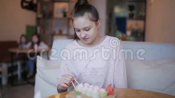 在咖啡馆里用筷子吃寿司的年轻女人视频的预览图