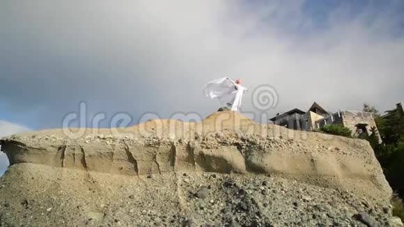 自由概念穿着白色衣服戴着围巾的女人站在岩石上跳舞飞行移动视频的预览图