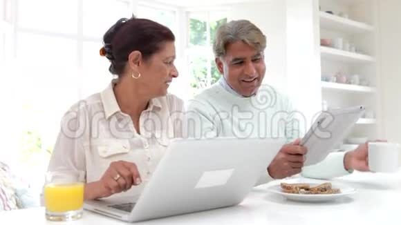 家中使用笔记本电脑和数码平板电脑的印度老夫妇视频的预览图