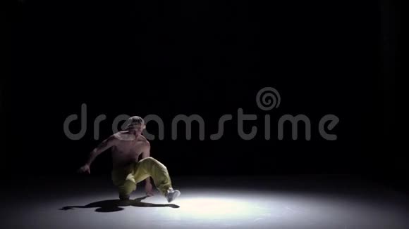 戴着帽子穿着黄色裤子的男子在黑色阴影中跳舞动作缓慢视频的预览图