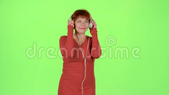 女人在耳机上听音乐绿色屏幕视频的预览图