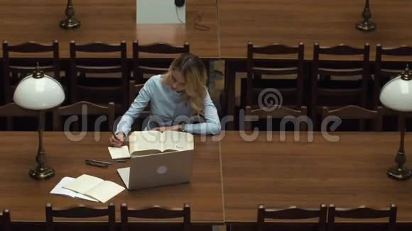 学生在图书馆里用书和笔记本电脑工作视频的预览图