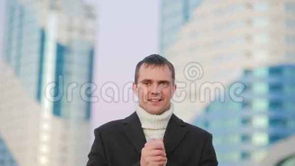在摩天大楼的背景下穿着外套在现代城市行走的时髦男人视频的预览图