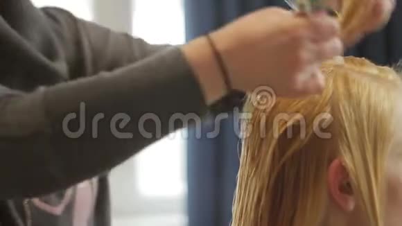 理发师剪了一个金发的女人剪发特写视频的预览图