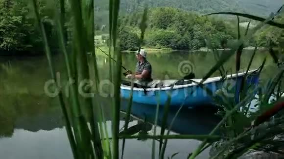 在美丽的大自然中从船上钓鱼的年轻人视频的预览图