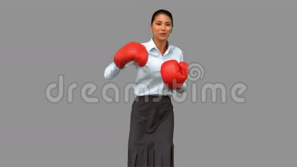 戴着拳击手套打灰色屏幕的女商人视频的预览图