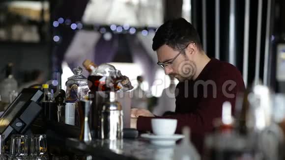 一个年轻人坐在酒吧里用平板电脑视频的预览图