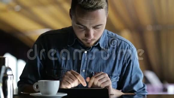 一个年轻人坐在酒吧里用平板电脑视频的预览图