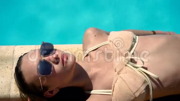 戴墨镜和泳衣的女人躺着日光浴视频的预览图