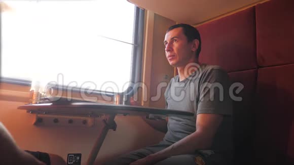 男人坐在火车车厢里手里拿着铁路喝着咖啡和茶慢动作视频两个人喝酒视频的预览图