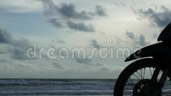 海边的女人剪影和停在海滩上的摩托车视频的预览图
