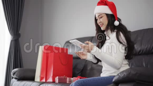 女士圣诞帽购物网上圣诞礼物与数字平板电脑客厅视频的预览图