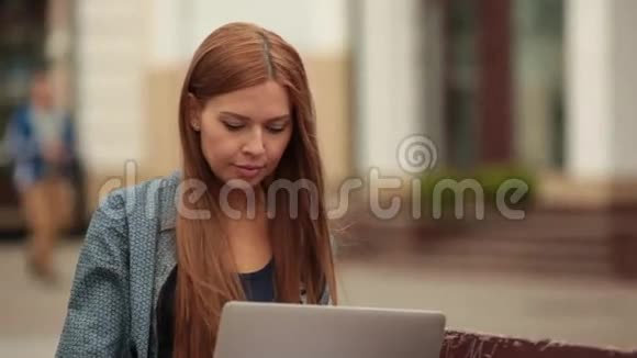 年轻时尚的女人带着笔记本电脑坐在长凳上工作视频的预览图