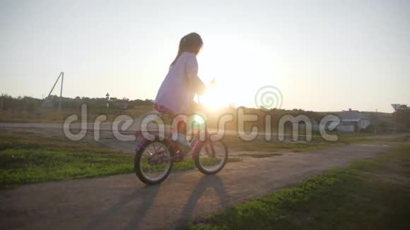 骑自行车的孩子在日落时骑自行车享受自由日落时骑自行车在乡下的女孩视频的预览图