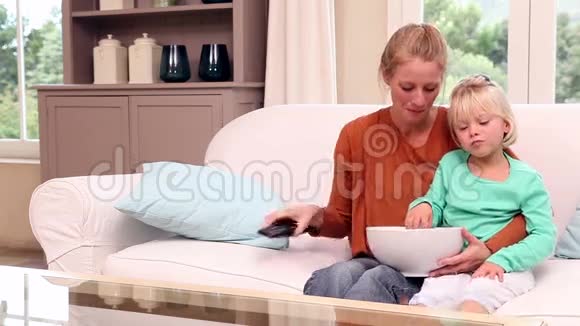可爱的小女孩和妈妈一起看电视视频的预览图