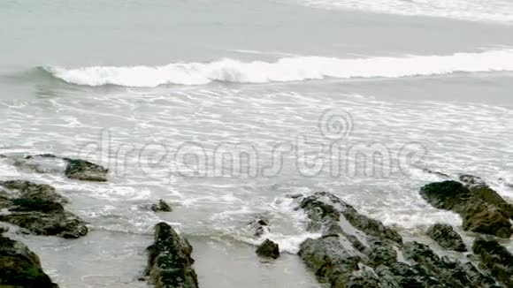 海浪在沙滩上滚过岩石视频的预览图