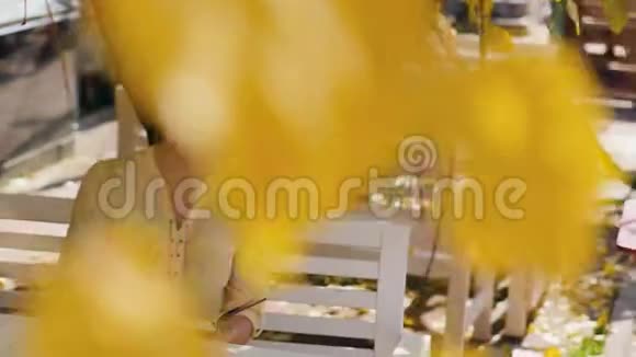 奇妙的秋景一位迷人的年轻女子开心地笑着坐在街边咖啡馆的一张桌子旁在里面记笔记视频的预览图
