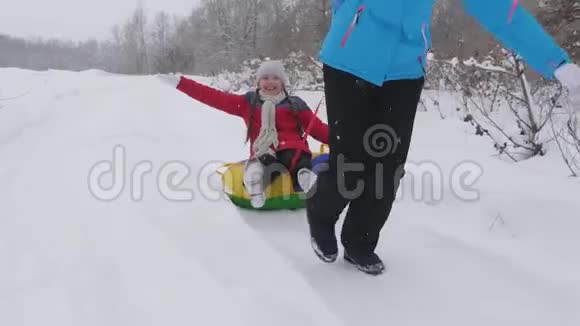 快乐的童年概念家庭寒假孩子和母亲在雪地里雪橇女儿和妈妈在冬天玩视频的预览图