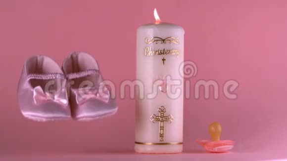 婴儿鞋落在点燃的洗礼蜡烛和奶嘴旁边视频的预览图