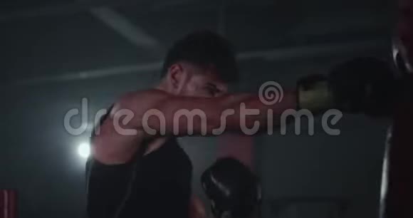 在一个大型拳击课上一个年轻有魅力的家伙穿着一个拳击袋有着完美的肌肉拳视频的预览图