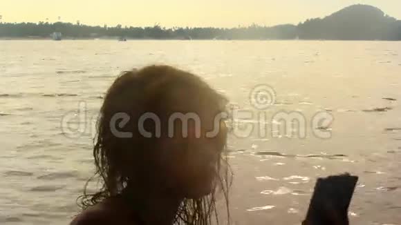 日落时分女孩在海滩上拍照视频的预览图