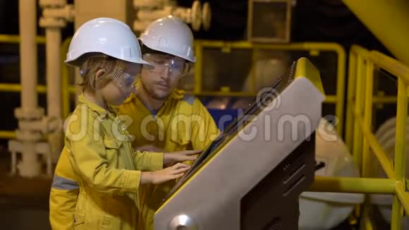 一个年轻人和一个小男孩都穿着黄色的工作服戴着眼镜戴着头盔在工业环境中戴着油视频的预览图