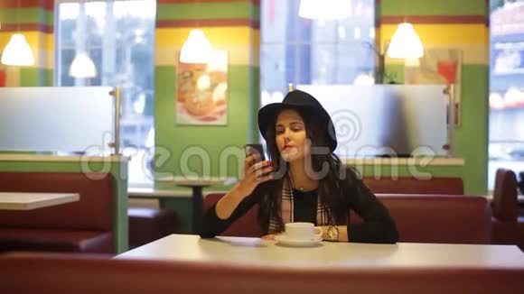 年轻女子坐在咖啡馆里读留言视频的预览图