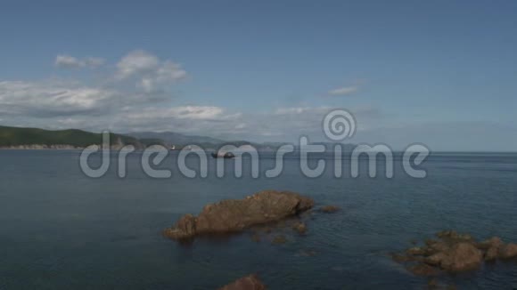 在日本海的海岸海滩上绿色石岩上的海面波浪视频的预览图
