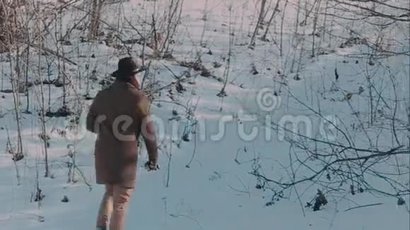 一个戴着毡帽和外套的人来到冬天的树林里毛毡制的棕色帽子和棕色外套视频的预览图