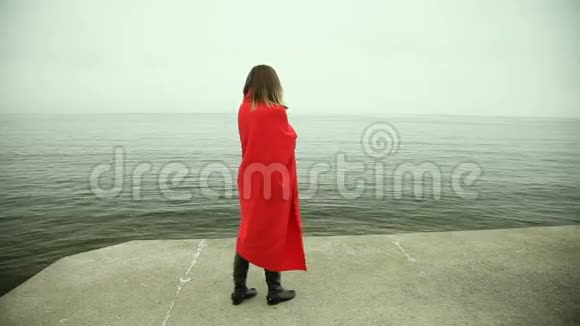 孤独悲伤的女孩穿着红毯在海边视频的预览图