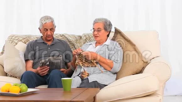 当她丈夫正在看报纸时一位老妇人正在编织视频的预览图