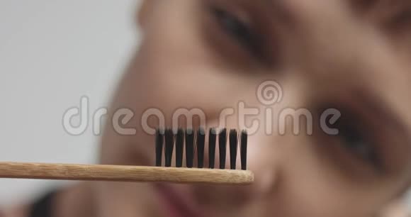 年轻漂亮的女人用黑色牙膏刷牙视频的预览图