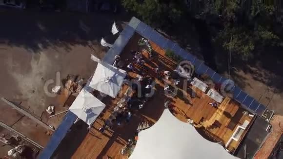 四架直升机拍摄夏季餐厅屋顶有白色帐篷阳光明媚人们树木视频的预览图