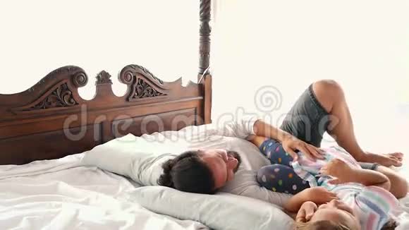 幸福的家庭我的小女儿跳到父亲的手臂上他们躺在床上视频的预览图