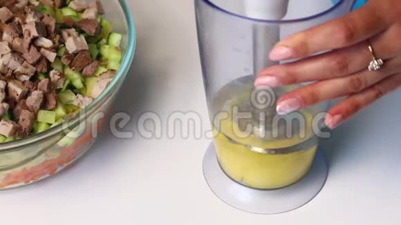 带有蔬菜和蛋黄酱的俄罗斯肉沙拉一个女人正在用搅拌机打蛋黄酱做沙拉视频的预览图