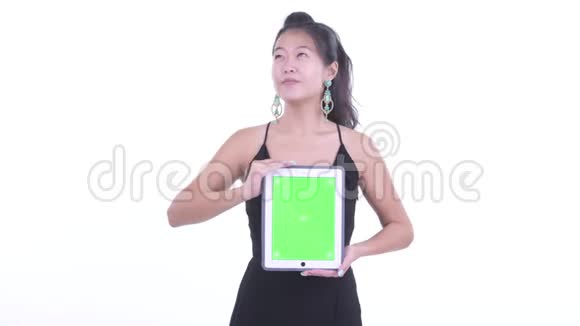 快乐美丽的亚洲女人一边思考一边展示数码平板电脑视频的预览图