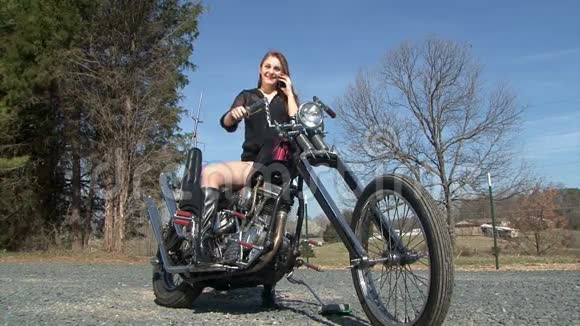 快乐的年轻女人在说手机摩托车视频的预览图