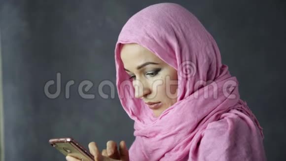 戴着粉红色头巾的年轻阿拉伯穆斯林美女在用手机说话视频的预览图