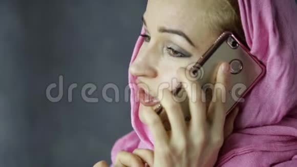 穿着粉色头巾的穆斯林美女在手机上聊天视频的预览图