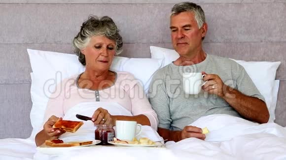 成熟的夫妇在床上享受早餐视频的预览图