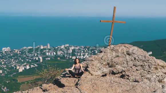 女旅行者在山上冥想坐在莲花的位置上的悬崖上视频的预览图
